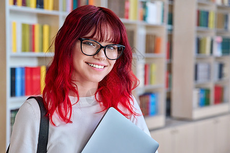 戴手提电脑背包眼镜的女大学生肖像 望着照相机笔记本幸福青年快乐微笑知识图书馆学校头发女孩图片