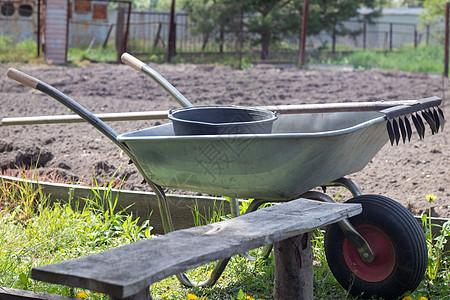 带两个把手和一个轮子的灰色金属花园独轮车 手推车在花园或花园里 园丁的手推车在后院 花园清洁房子车轮土地工具农场家庭生活风光孤轮图片