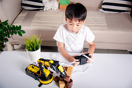 快乐的亚洲小男孩使用遥控器 玩机器人机器臂来捡木块 笑声木头机器科学乐趣学校文化创新工程宽容手臂图片