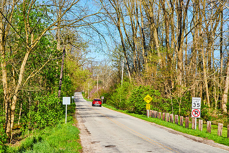 红车在春末中西部沿路行驶时使用新树叶图片