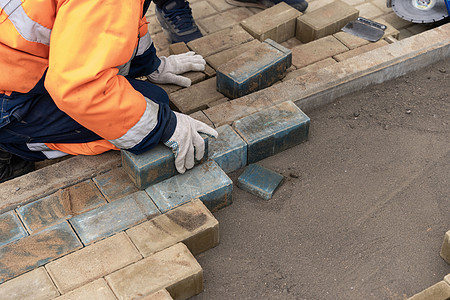 从事保护性工作服的工人铺设了铺路板建筑学院子建筑地面平板水泥瓦工人行道石工小路图片
