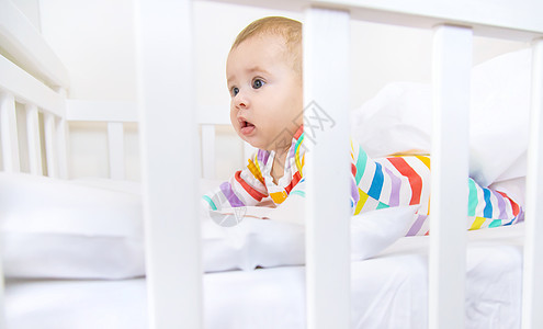 婴儿床里的婴儿上床睡觉 有选择地集中注意力微笑卧室童年母亲婴儿床女士蓝色玩具新生房间图片