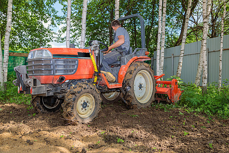 使用小型拖拉机的农民为草坪解开土壤 土地耕种 地面平整工作男人农业坑洞花园石头耕作机器舵柄栽培图片
