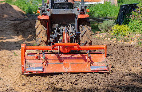 使用小型拖拉机的农民为草坪解开土壤 土地耕种 地面平整坑洞花园农业工作男人舵柄场地生育力耕作耕地图片