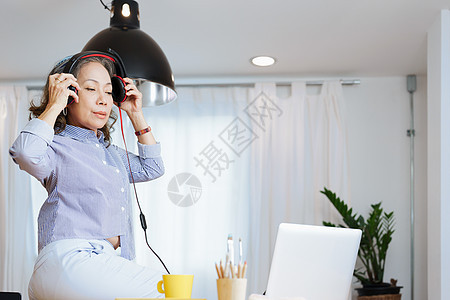 放松时间 一位老妇人的肖像快乐地听音乐 在电脑会议之间放松商务女士互联网笔记本摄影耳机商业女性娱乐人士图片