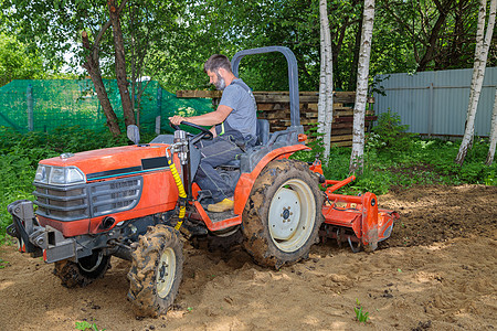 使用小型拖拉机的农民为草坪解开土壤 土地耕种 地面平整耕作修炼者花园栽培场地生育力工作男人农业机械坑洞图片