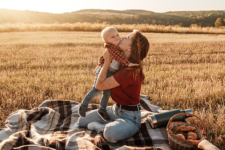 快乐的妈妈和她的小儿子在阳光明媚的日落时分在城外的田野里享受夏日周末公园母性乐趣蓝色男生晴天衣服婴儿孩子绿色图片