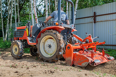 使用小型拖拉机的农民为草坪解开土壤 土地耕种 地面平整生育力男人石头工作舵柄农业机械坑洞农业花园耕作图片