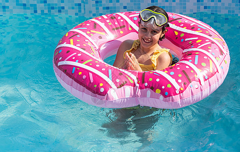 漂亮的小女孩在户外游泳池游泳 玩得开心 带充气环太阳童年喜悦冒险水池快乐圆圈玩具蓝色孩子图片