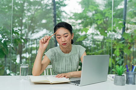 年轻的亚洲女商务人士坐在办公桌前 手持铅笔思考和规划业务战略的年轻女商务人士商业工人公司经理桌子人士电脑报告办公室工作图片