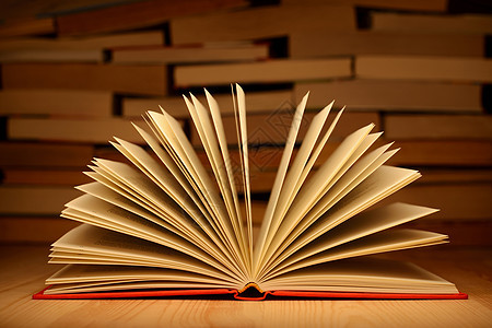 木制桌上的开放书和背景上的一堵书墙背景图片
