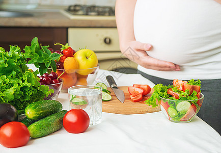 孕妇吃蔬菜和水果 有选择性地集中注意力女性沙拉厨房母亲父母横幅素食主义者腹部成人营养图片