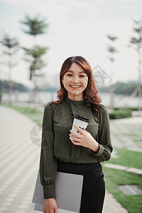 一个快乐的女人 拿着银纸贴板走着 手里拿起咖啡的喜悦女神图片