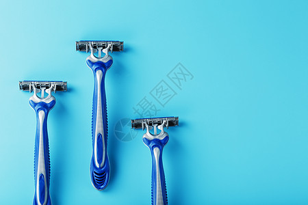 蓝剃须机在蓝色背景上排成一排 带冰块安全男人护理用品腐蚀刮胡子机器剃须刀工具宏观图片