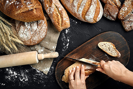 女人用手在生锈的木板上切面包 上面有小麦耳朵和刀子早餐农村背景高架面包师女性食谱糕点美食产品图片