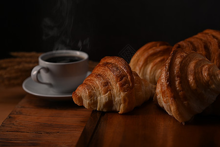 木制木板上的美味羊角面包和热咖啡准备供应早餐 早餐 面包烘焙产品咖啡馆概念图片