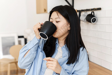 在厨房里 一位迷人的韩国女人 喝着咖啡或茶图片