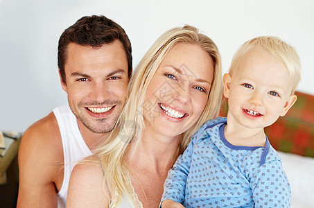 完美的家庭肖像 父母双亲坐在床上时在摄像机上与小儿子一起笑着微笑图片