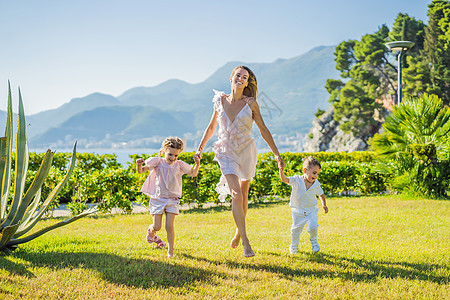 夏日 快乐的年轻母亲和两个小孩 男孩和女孩在绿色公园里玩接球游戏 童年 为人父母 幸福的概念婴儿跑步草地孩子儿子家庭团体喜悦阳光图片