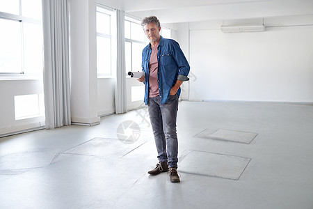 想象这个空间的美好景象 一个成熟男人的肖像 他站在一个空房间里拿着建筑布置图图片