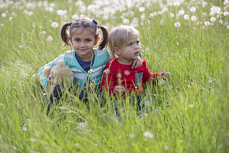 孩子们坐在草地上 在田地里的朋友们也一起来参加盛会青年女孩女性享受阳光友谊婴儿玩具孩子乐趣图片