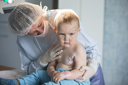 一个小男孩护士治疗烧伤 医院里的一个孩子受伤了 医生治疗婴儿 小医院病人面具衣服手术伤口程序护理医疗办公室持有病房姐姐图片