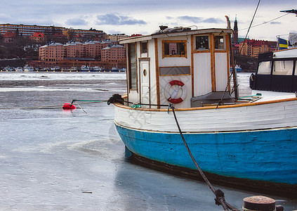 冬季在冰冻河上停泊的小型渔船 船上有蓝色船体图片