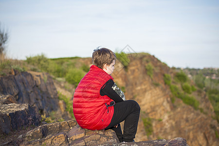 一个孩子坐在悬崖顶上 看着下面发生的事情 从落基山顶的全景 俄罗斯 罗斯托夫地区 顿河世界第七大奇迹天空绿色纪念碑城市蓝色男生国图片
