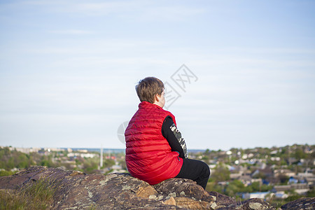 一个孩子坐在悬崖顶上 看着下面发生的事情 从落基山顶的全景 俄罗斯 罗斯托夫地区 顿河世界第七大奇迹蓝色天空男生森林城市旅行纪念图片