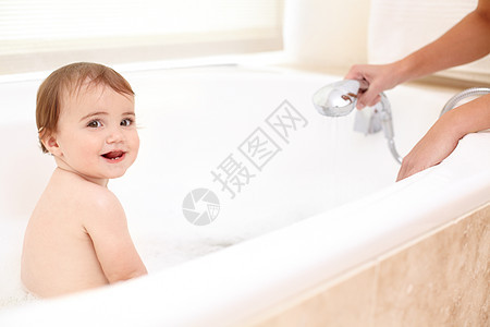 洗澡时间很好玩 一个可爱的女婴在洗澡时的肖像 她妈妈看着她图片