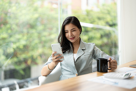 美丽的年轻亚洲女商务人士在办公室使用计算器和财务文书工作时使用电话技术职业成人女士笔记本白色商业女孩手机商务图片
