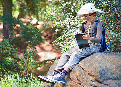 一个小男孩手拿着一本书 坐在石头上 在看猫头鹰的书图片