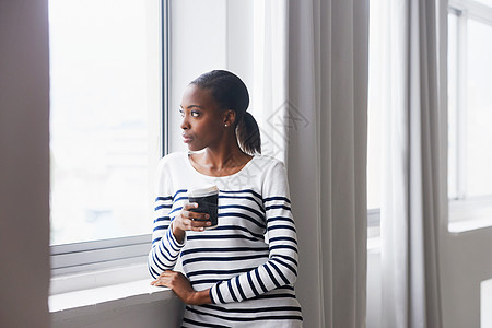 一位深思熟虑的年轻女子在咖啡休息时从窗外仰望着她 这名年轻女士正在寻找图片