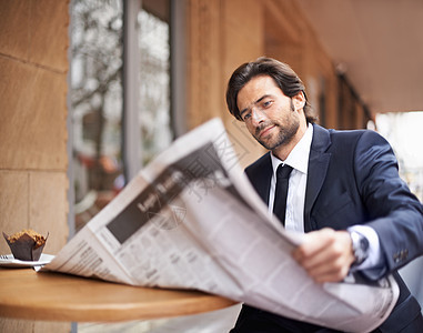 一位年轻的商务人士在咖啡店的户外看报纸 在一家咖啡馆里读报纸图片