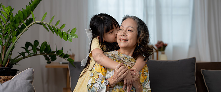 孙子孙女亲吻爱 她成熟的女人 在沙发上在家学前祖母成人退休女性微笑快乐拥抱幸福女孩家庭喜悦图片