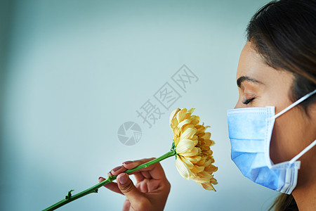我好像闻不到任何味道 一个年轻女人在戴外科面具时 闻着花的气味图片