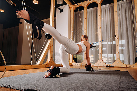身穿运动制服的女孩在模拟器上做锻炼 以拉伸人体活力肌腱运动服力量自重紧张肌肉成人健身房运动员图片