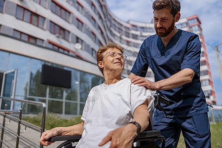 护士步行时在医院院子里与轮轮椅病人交谈护理轮椅成人职业退休人士卫生女士医生健康图片
