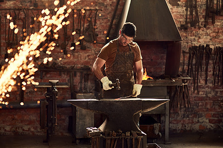 金属就是这样变得坚固的 一位英俊的年轻金属工人在焊接车间用大锤击打热金属棒的镜头图片