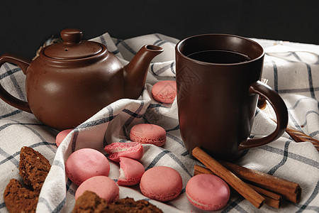 茶壶和杯子 用分散的粉红面纱在厨房布上咖啡店饼干糖果甜食背景桌子深色咖啡小吃饮料图片