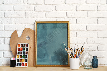 相片框 用画家的工具在木制桌边与白砖墙对齐照片艺术相框装饰学校工作刷子创造力爱好画笔图片