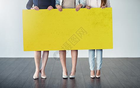 等待来自企业的消息 裁剪工作室拍摄的一群女商务人士举着一张空白的黄色标语牌图片