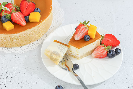 一块芝士蛋糕和芒果放在盘子上 一个茶叉装饰着浆果和灰色背景的鲜花 健康的食物菜单甜点美食香草薄荷早餐餐厅生日蛋糕奶油图片