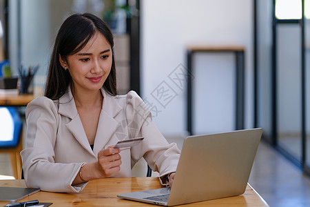 在线购物和互联网支付 美丽的亚洲女性正在使用信用卡和笔记本电脑在数字世界中在线购物或办事技术卡片享受女士信用成人银行业金融店铺零图片