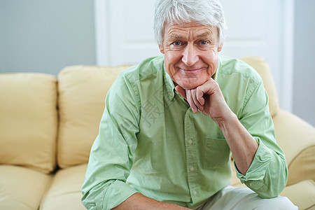 快乐的日子来了 一个坐在沙发上的幸福老人的肖像 他在家里图片