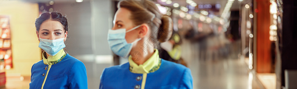 在机场携带旅行邮袋的医务口罩飞行服务员;图片