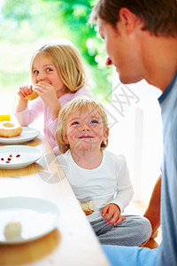 微笑的小男孩与他的父亲和妹妹一起吃早餐 一个微笑的小男孩与他的父亲和妹妹一起吃早餐的画像图片