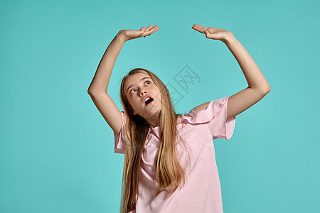 一个穿着粉红色T恤的金发美女少女 穿着蓝色背景装扮的片场肖像乐趣大学金发女郎成人工作室女孩教育姿势头发孩子图片