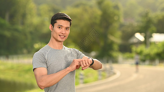 运动人正在设置和检查他的心心率数据 在公园的早上锻炼时在智能观察上图片