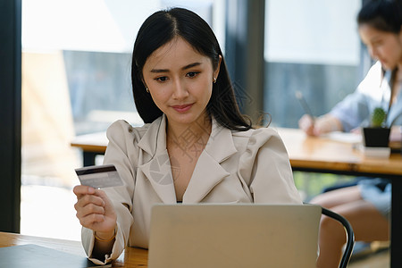 在线购物和互联网支付 美丽的亚洲女性正在使用信用卡和笔记本电脑在数字世界中在线购物或办事网络卡片互联网商业摄影技术手机银行业零售图片